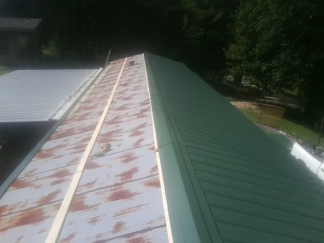 Old rusted panels beside newly installed green metal roofing — Wind Damage Roof Repair by Roofing Brothers in Drumore