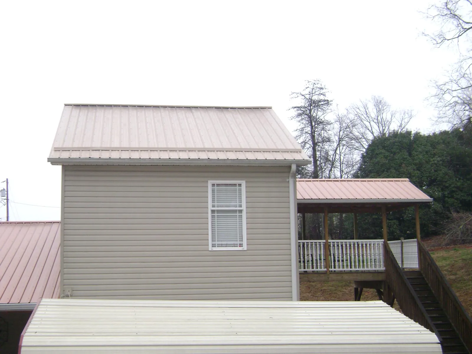 Tan metal roofs on a two story addition and attached porch, from a Roof Replacement job in Drumore